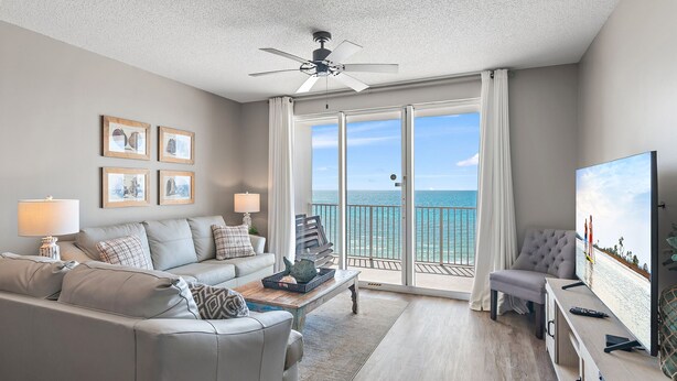 A modern living room with a sofa, coffee table, and TV, featuring a balcony with a view of the sea. - Majestic Sun B613*Remodeled* Gulf Views*Beach Gear*Hot Tubs/Heated Pools* Tennis (Miramar Beach)