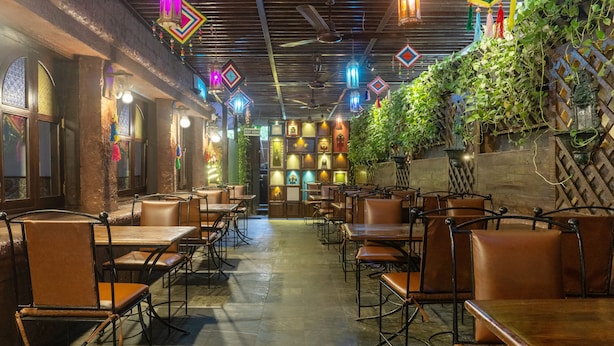 A restaurant interior with booths and tables, decorative lanterns, and a wall with greenery. - Treebo Bhairavee, Baner (Pune)