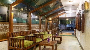 A seating area with wooden benches and tables, a glass enclosure, and a view of the outside. - Treebo Bhairavee, Baner (Pune)