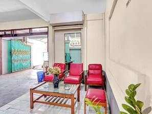 A room with a glass coffee table, red chairs, a vase with flowers, and a green gate.