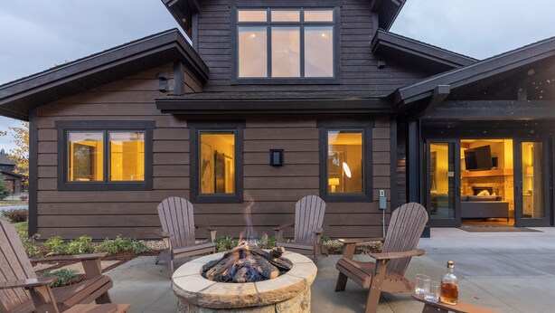 Une maison moderne avec un foyer au centre, entourée de chaises en bois.