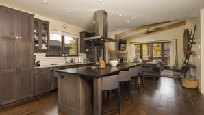 Une cuisine spacieuse dotée d’un grand îlot central, de meubles de cuisine en bois foncé et d’une cuisinière moderne.