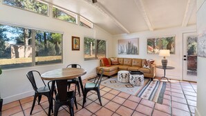 A spacious living area with a large window, a round wooden table, and a beige sofa. - Remodeled, Centrally Located in Sedona 2 Bed / 2 Bath Home (Sedona)