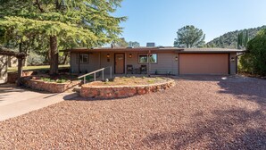 A single-story house with a gravel driveway and a stone retaining wall. - Remodeled, Centrally Located in Sedona 2 Bed / 2 Bath Home (Sedona)