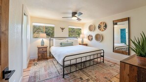 A bedroom with a bed, bedside tables, a ceiling fan, and a large mirror. - Remodeled, Centrally Located in Sedona 2 Bed / 2 Bath Home (Sedona)