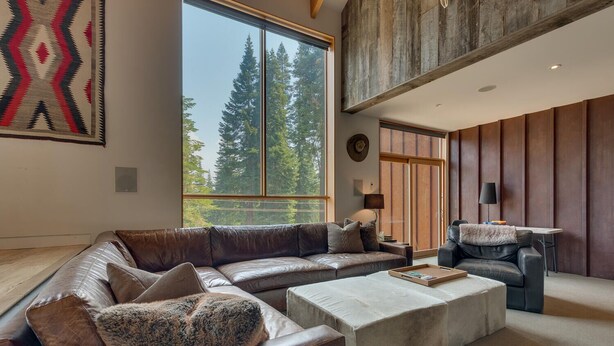 A modern living room with a large sectional sofa, a coffee table, and a fireplace. - Mod Haus by Tahoe Getaways - West Shore w/ Private Beach Access & Pier + Close to Lake! (Homewood)
