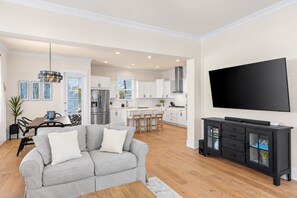 Un salon moderne avec un canapé gris, un téléviseur à écran plat et un meuble de rangement noir pour les appareils multimédias.