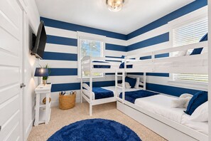 A room with bunk beds, a television, a lamp, and a window with blinds. - Casa Del Sol - 3BR/2.5BA Grande Pointe Home - Sleeps 9 - Community Pool (Inlet Beach)