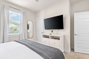 Une chambre à coucher avec un lit, une télévision, une commode et un miroir.