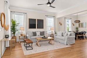 A spacious living room with a sofa set, a coffee table, and a dining area with chairs. - Casa Del Sol - 3BR/2.5BA Grande Pointe Home - Sleeps 9 - Community Pool (Inlet Beach)