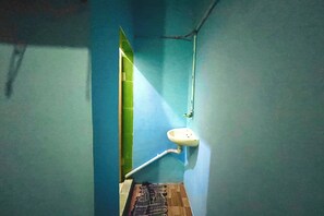 A bathroom with a sink, a green door, and a visible pipe.