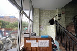 A room with a window, a staircase, a signboard, and a scooter outside. - Faster Inn 2 by Zuzu (Medan)