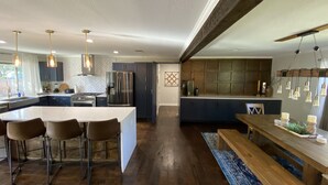 Une cuisine moderne dotée d’un îlot central, de tabourets de bar et d’un coin repas avec un banc en bois.