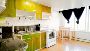 A kitchen with wooden flooring, a white stove, and green cabinets. - Downtown City Condo (Tacoma)