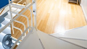 A modern living room with a staircase, wooden flooring, a sofa, a lamp, and a TV. - Downtown City Condo (Tacoma)