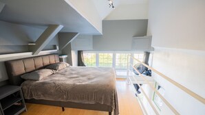 A bedroom with a bed, a nightstand, a dresser, and a window with a view of trees. - Downtown City Condo (Tacoma)
