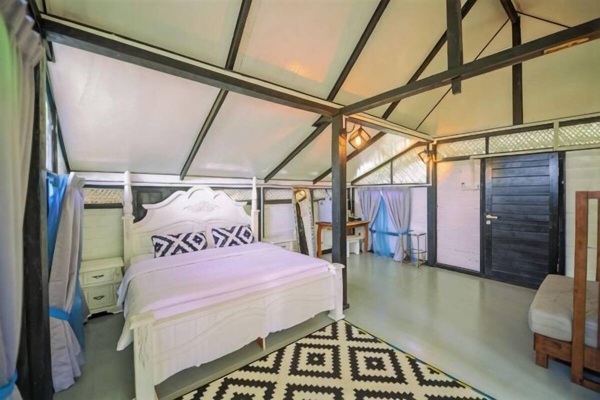 Una habitació tipus tenda amb un llit, una banca i una taula petita.