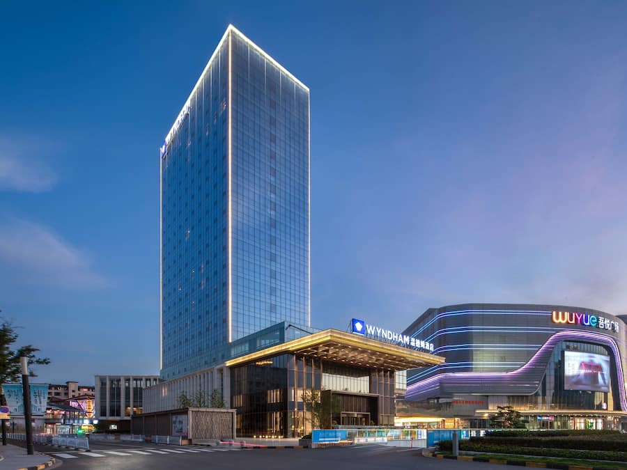 A modern hotel with a prominent vertical tower and a curved building with illuminated signage.