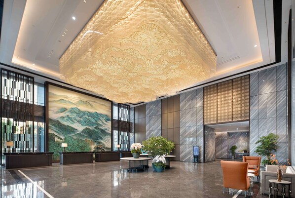 A spacious lobby with a large mural, a reception desk, seating area, and a decorative ceiling. - Wyndham Changzhou Liyang (Changzhou)
