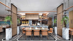 Un restaurante moderno con zona central de comedor, bar y cocina.