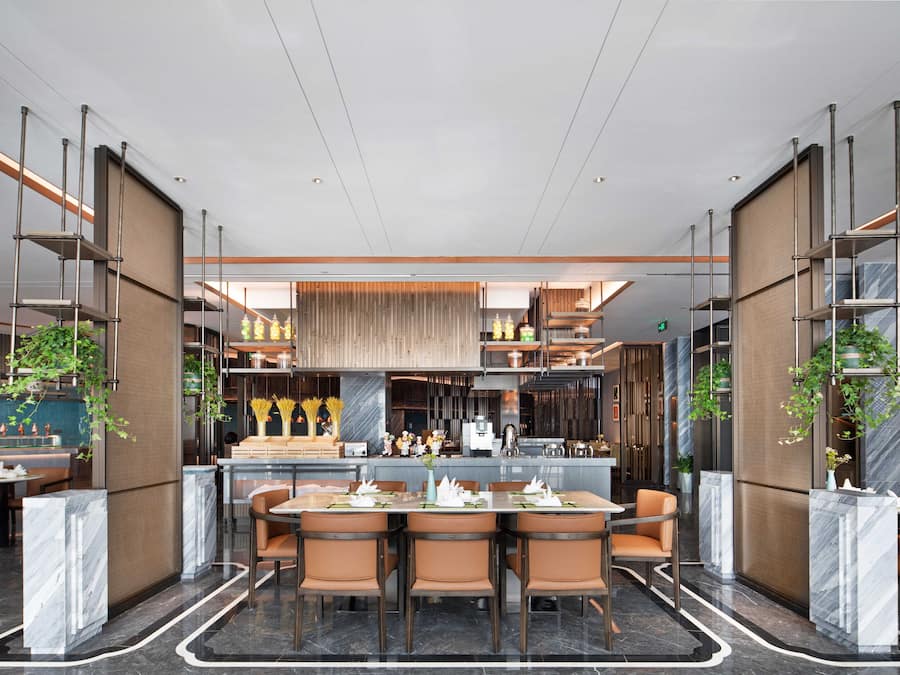 A modern restaurant with a central dining area, bar, and kitchen.