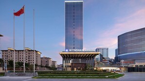 Un hotel moderno con una fachada de vidrio llamativa, una entrada bien iluminada e izado de bandera.