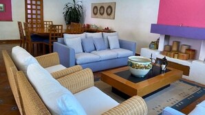 A living room with a sofa set, a coffee table, a dining area with a table and chairs, and a potted plant. - Finca El Paraiso  (Tepoztlán)