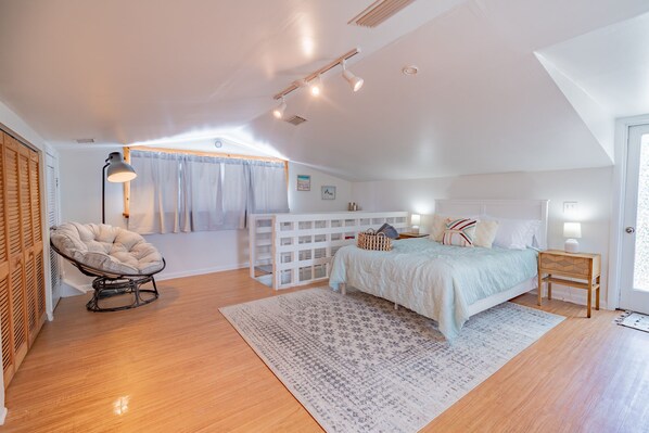 Une chambre à coucher avec un lit, une chaise, un bureau et une fenêtre avec des rideaux.