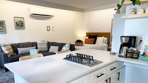 Een moderne keuken met een centraal eiland, witte kasten en een koffiezetapparaat.