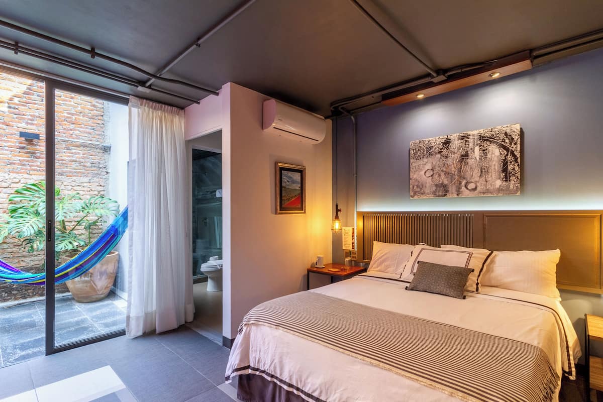 Habitación de hotel moderna con una cama grande, vistas al exterior, una hamaca y un cuadro en la pared.