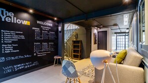 Een modern interieur met een zwarte muur waarop faciliteiten staan vermeld, en een trap naar een hoger niveau.