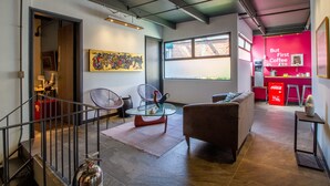 Een moderne leefruimte met een glazen salontafel, een bank en een rode accentmuur.