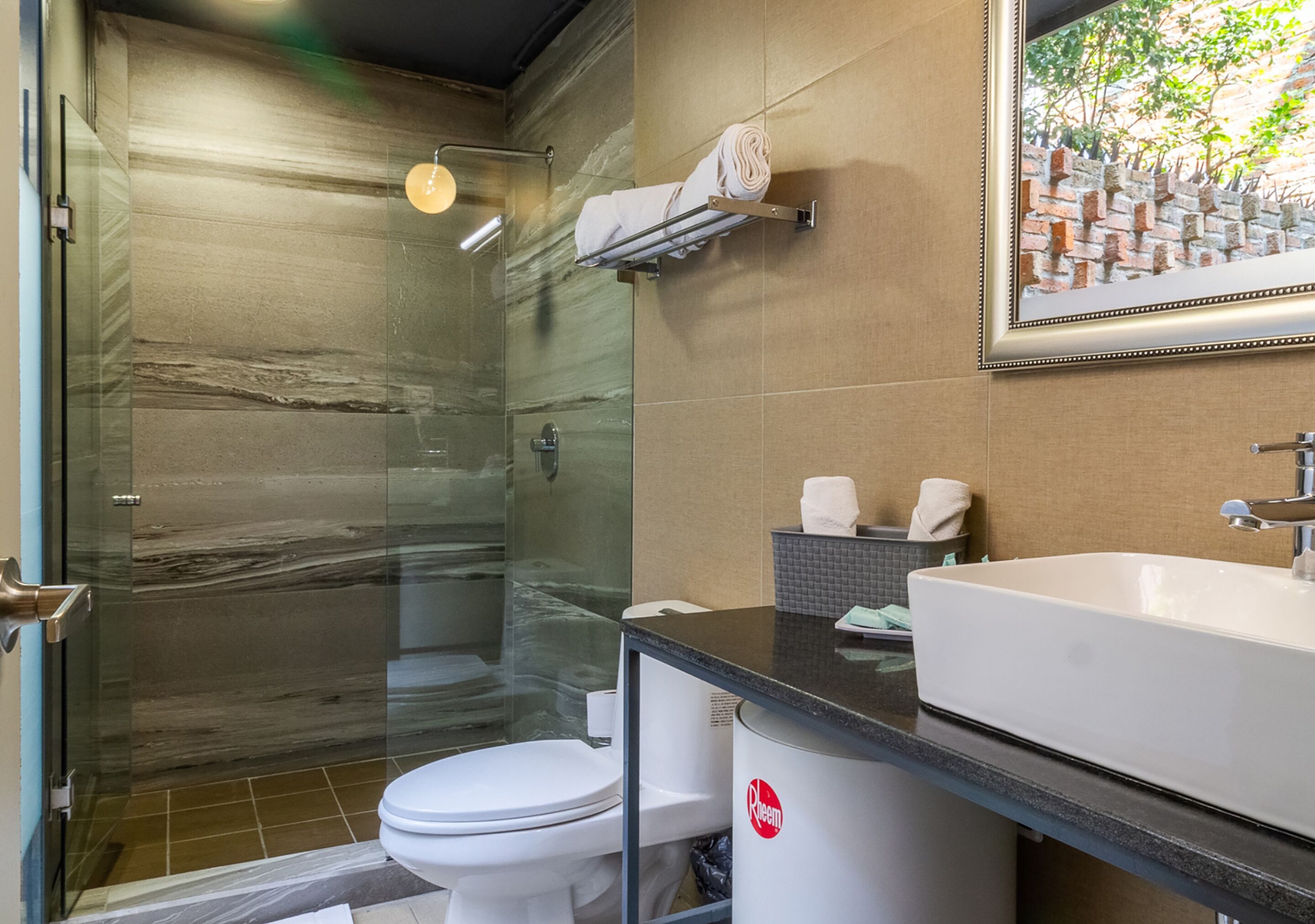 A modern bathroom with a glass-enclosed shower, a white toilet, and a large sink with a black countertop.