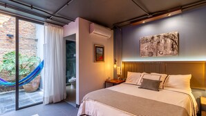 Een moderne hotelkamer met een groot bed, uitzicht, een hangmat en een schilderij aan de muur.