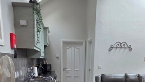 A modern kitchen with a dining area, a grey sofa, and a patterned rug. - Magical 3-bed Stone Built Cottage - Sleeps 6 (Ballynahinch)