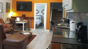 A compact living space with a kitchenette, a dining area, and a bedroom. - Magical 3-bed Stone Built Cottage - Sleeps 6 (Ballynahinch)
