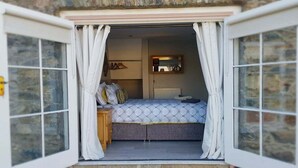 A bedroom with a bed, a dresser, and a radiator. - Magical 3-bed Stone Built Cottage - Sleeps 6 (Ballynahinch)
