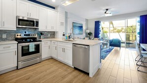 A modern kitchen with white cabinets, stainless steel appliances, and a large island.