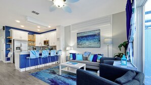 A modern living room with a sofa, coffee table, and a view of the kitchen.