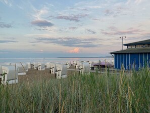 A beach with rows of numbered beach chairs and a blue building in the background. - Vacation apartment on the Szczecin Lagoon with garden and terrace (Ueckermünde)