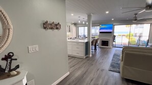 A spacious living area with a kitchen, a fireplace, and a balcony with a view.