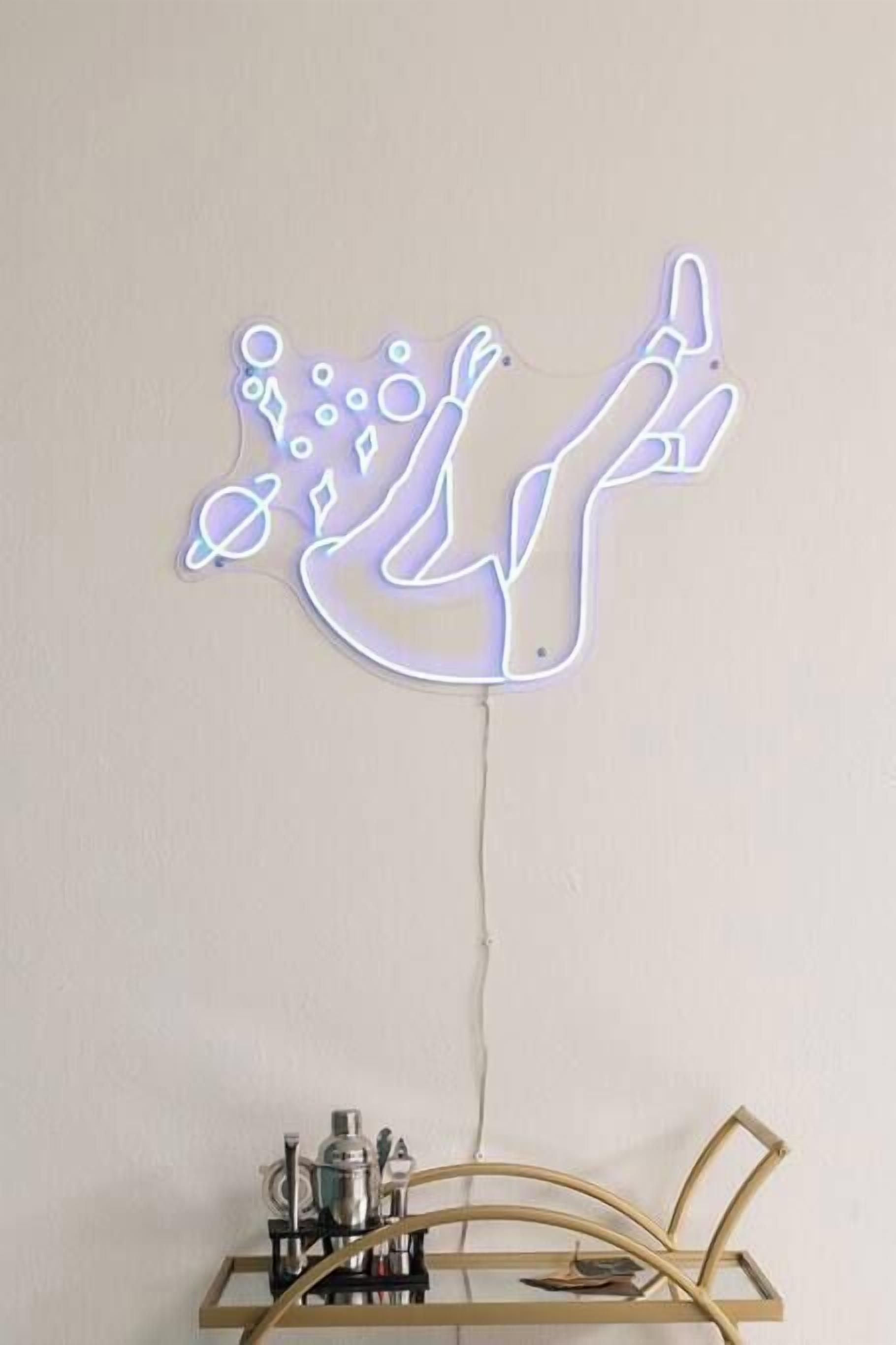 A neon sign of a dancing figure on a wall.