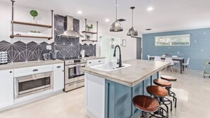 Una cocina moderna con una isla central, taburetes de bar e iluminación colgante.