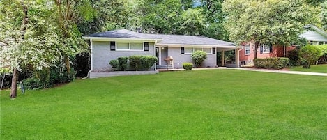 A single-story house with a front porch, a well-maintained lawn, and a brick exterior.