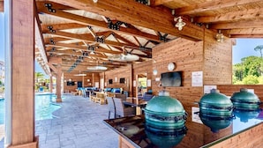 Un'area esterna coperta con piscina, sedute in legno e barbecue.