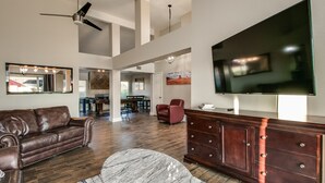 A spacious living room with a leather couch, a marble coffee table, a wooden cabinet, and a flat-screen TV mounted on the wall. - Spectacular Hillside Fountain HIlls home + Resort Backyard and Views! (Fountain Hills)