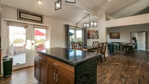 A spacious kitchen with a dark granite island, wooden cabinets, and pendant lighting. - Spectacular Hillside Fountain HIlls home + Resort Backyard and Views! (Fountain Hills)