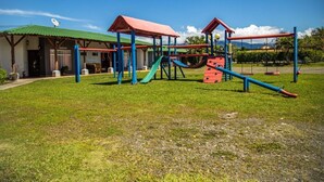 A playground with a slide, climbing structures, and a covered seating area. - Hotel Rancho Leon a Place to Stay | Room 12 (Quepos)