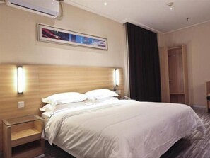Relax in a spacious room with a large bed, bedside table, and framed artwork.