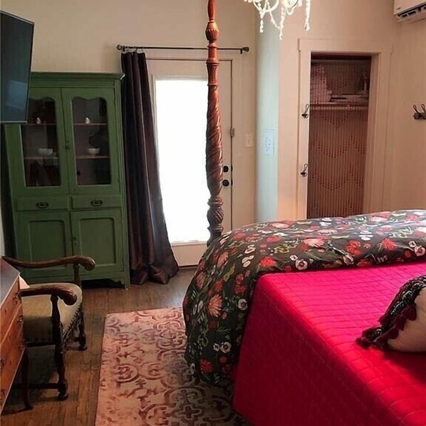 A bedroom with a four-poster bed, a green cabinet, a wooden chair, and a patterned rug.